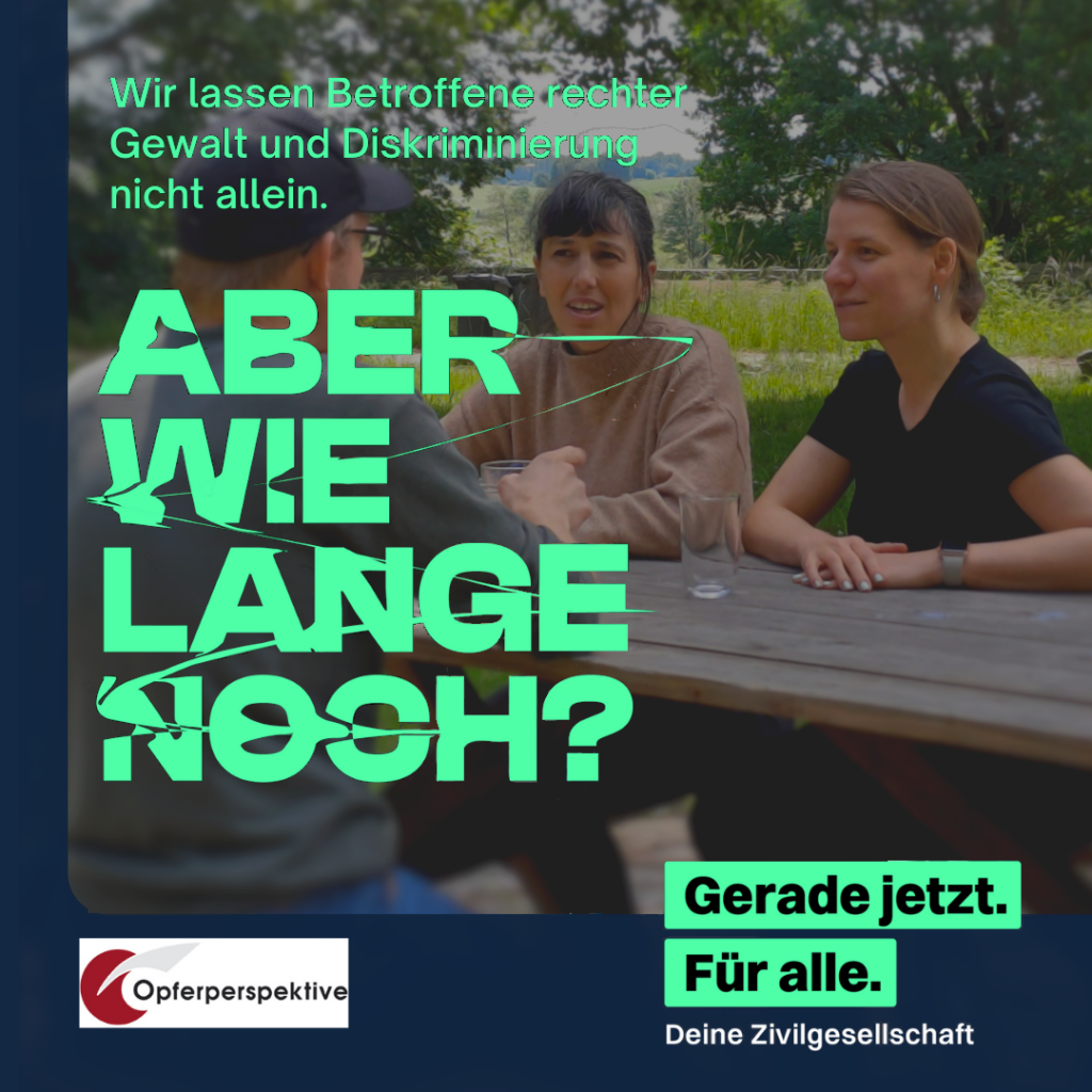 Foto von einem Beratungsgespräch am Tisch im Freien, drauf zwei Berater:innen, die einer Person mit Basecap und grauem Pullover gegenübersitzen.